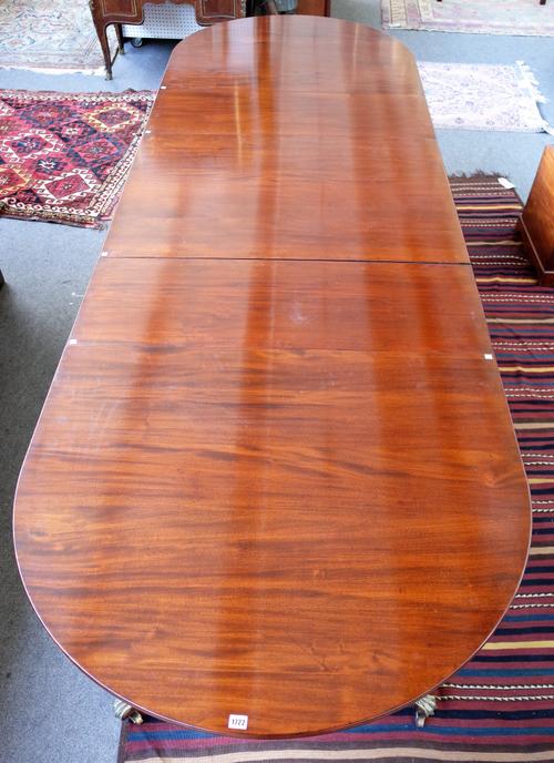 A Regency style mahogany triple pillar D-end extending dining table on three spiral fluted columns and ten foliate carved downswept supports including