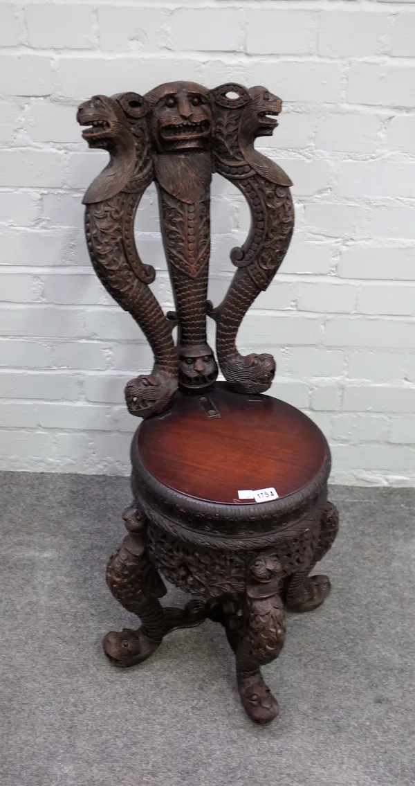 A late 19th century Burmese hardwood chair, the back carved with a trio of mythical beasts over round seat, 44cm wide x 89cm high.