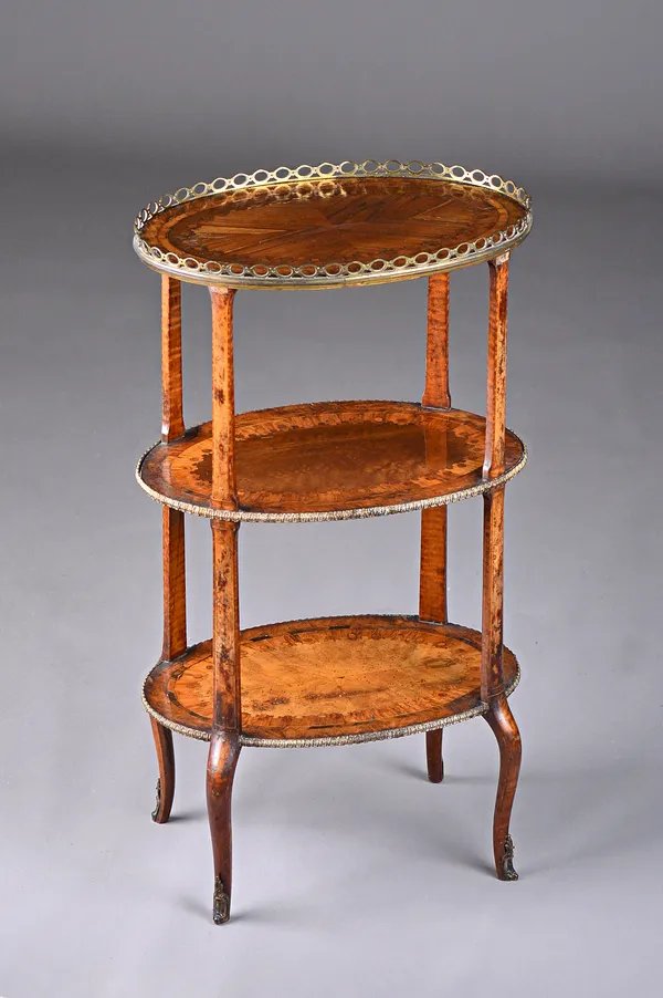 A Louis XVI style parquetry inlaid gilt metal mounted oval three tier etagere with a variety of specimen woods including kingwood, tulipwood, walnut a