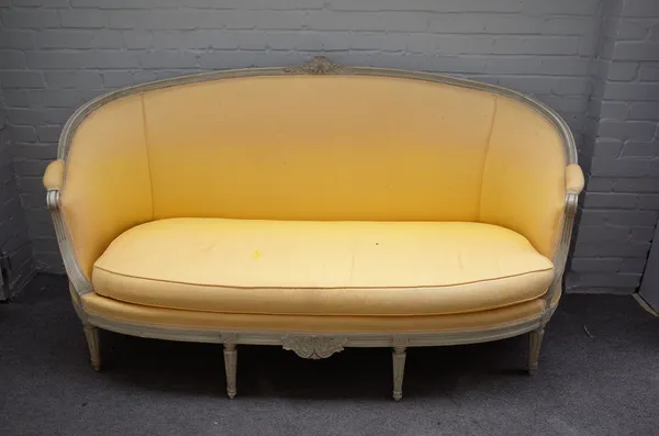 A Louis XVI style tub back sofa, with cream painted moulded frame, on tapering fluted supports, 180cm wide x 104cm high.