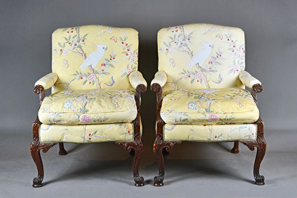 A pair of Edwardian carved mahogany framed open armchairs of George III Gainsborough design, upholstered with parakeets and butterflies amongst flower