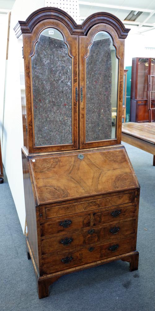 A Queen Anne style featherbanded figured walnut double dome top bureau bookcase, the pair of mirrored doors over a fitted and welled interior over two