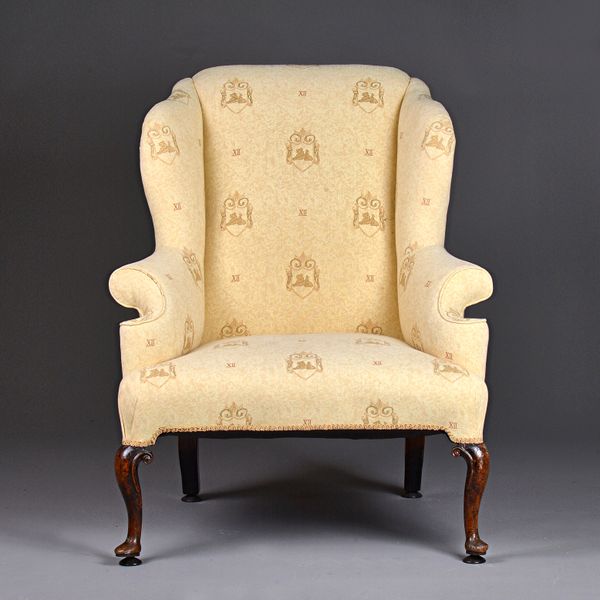 A Queen Anne walnut framed armchair, the outswept wing back over straight front seat on scrolled cabriole supports, 90cm wide x 110cm high. Illustrate