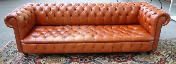 A large brown leather button upholstered Chesterfield sofa on turned feet, 255cm wide x 81cm high x 86cm deep.