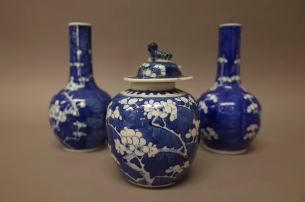 A pair of Chinese blue and white bottle vases and an oviform jar and cover, circa 1900, each painted with branches of prunus against a `cracked-ice' g