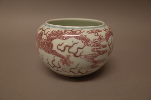 A Chinese porcelain compressed circular vase, blue six-character Kangxi mark but later, painted in underglaze-red and blue with two dragons amongst cl