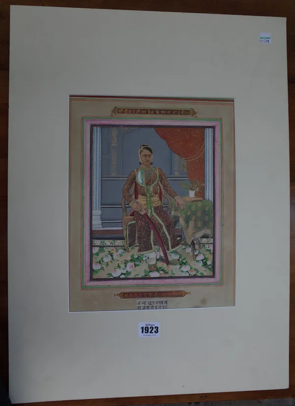 An Indian painting of a ruler, circa 1900, possibly painted over a printed base, depicting a young man seated in an interior beside a table, holding a