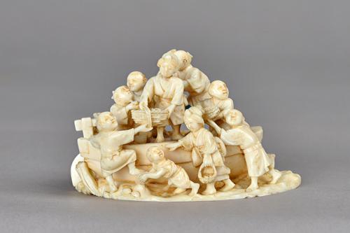 A Japanese ivory group of figures and a boat, Meiji period, carved with five men woman in the boat carrying baskets of provisions, one man seated play