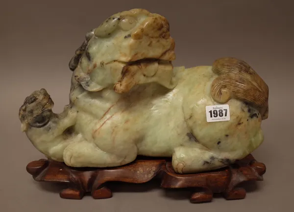 A large Chinese jade group of a recumbent Buddhist lion and cub, 20th century, 35cm. length, wood stand, (2).