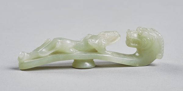 A Chinese celadon jade belt hook, Qing Dynasty, with dragon head terminal and with a chilong clambering up the shaft, 11cm. length. Illustrated. Prove