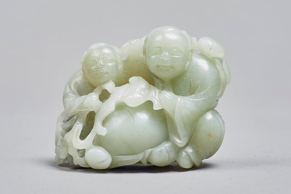 A Chinese celadon jade group of the Hehe Erxian, Qing Dynasty, the smiling twins carved seated with a bat and branches of fruiting peach, 5.5cm. high.