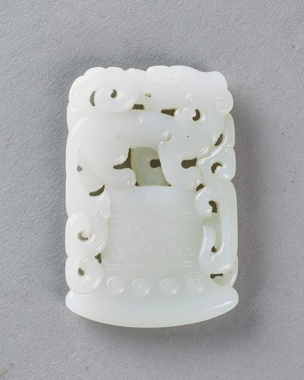 A Chinese white jade plaque, Qing Dynasty, carved and pierced with a dragon standing on a bell, 6.5cm. high. Illustrated. Provenance; From a distingui