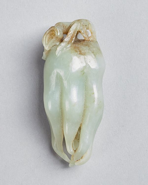 A Chinese celadon jade finger citron, Qing dynasty, naturally carved with curled finger-like tendrils, the stone with russet inclusions, 7cm.length. I