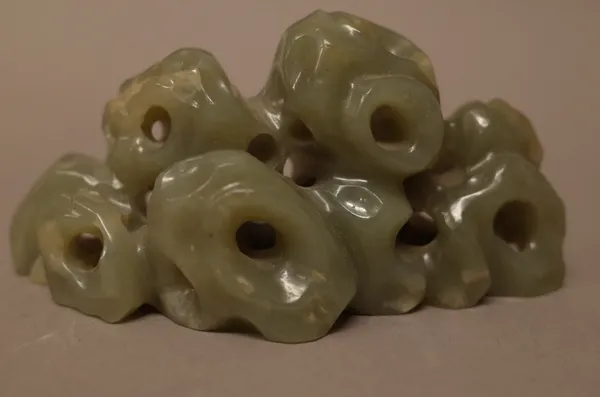 A Chinese celadon jade brush rest, carved as a group of pierced rocks, 11.5cm. wide.Provenance; From a distinguished UK scholar and collector ( lots 1