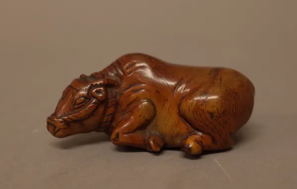 A Japanese wood netsuke of a recumbent ox, probably 19th century, carved lying with head turned slightly, unsigned, 6.5cm. length, boxed.