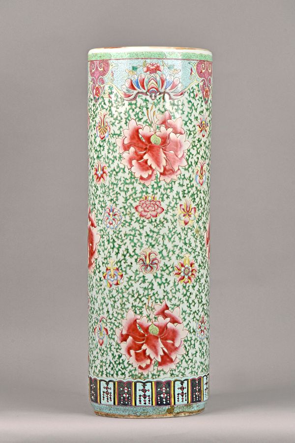 A Chinese famille-rose cylindrical stick stand, circa 1900, colourfully painted with flowers and green tendrils, 66cm. high. Illustrated.