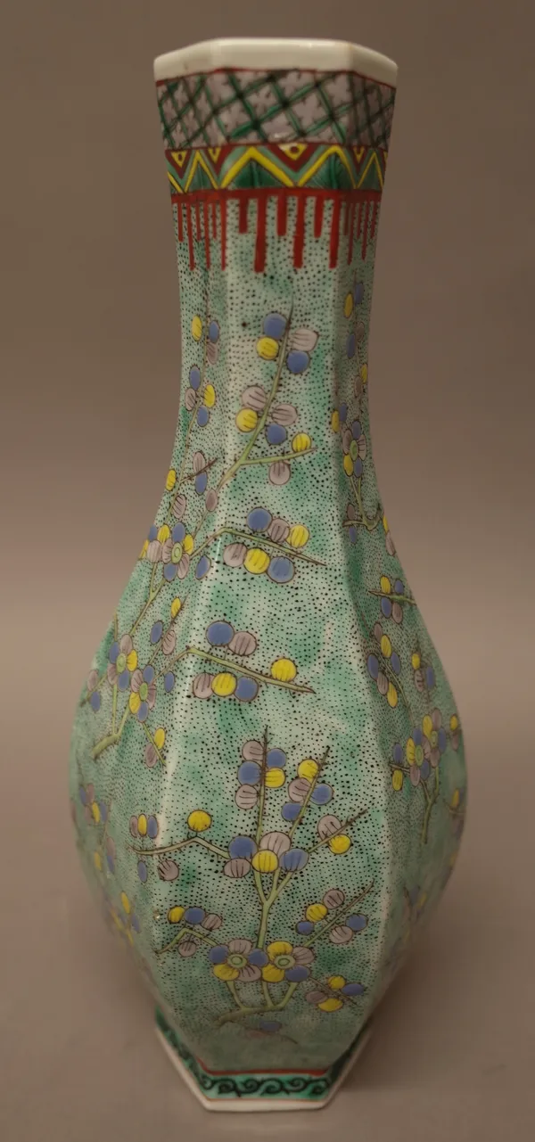 A Chinese porcelain hexagonal bottle vase, late 19th century, painted with branches of prunus against a green and black seeded ground, four character