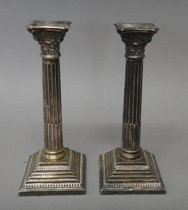 A pair of silver table candlesticks, each formed as a Corinthian column, raised on a stepped square base, having beaded borders, (loaded), Birmingham