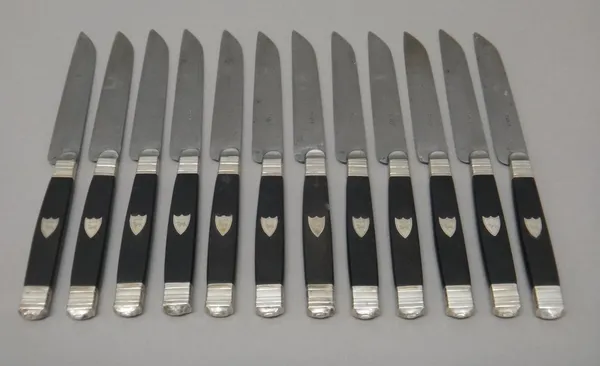 A French set of twelve steel bladed knives, the ebonised handles with applied crested shield motifs, the blades detailed Paris, with a fitted case.