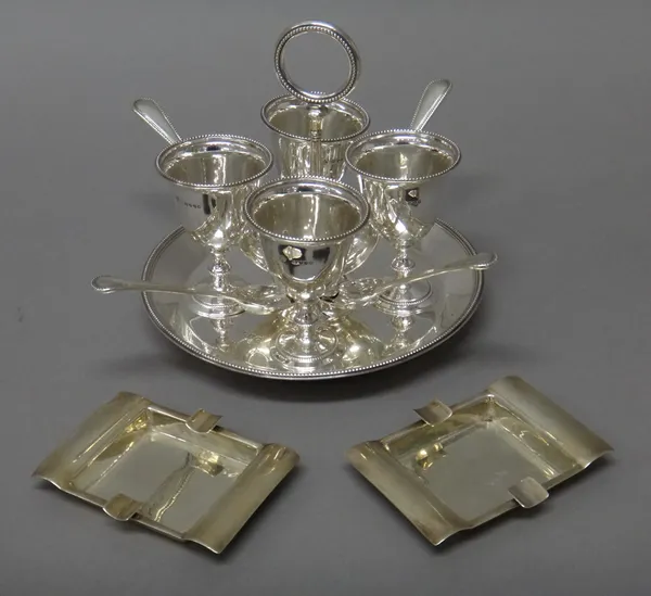 A Victorian silver egg cruet stand, raised on four bun feet, the circular stand with a loop shaped handle, London 1887, with four egg cups, London 188