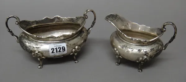 A silver twin handled sugar bowl, of compressed oval form, having a shaped rim, raised on four scrolled feet, together with a matching milk jug, Sheff