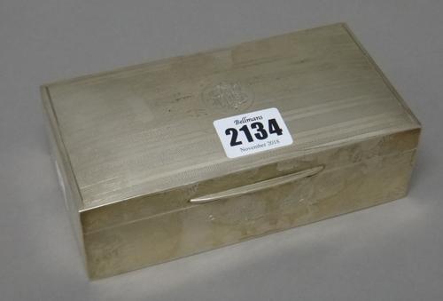 A silver rectangular table cigarette box, wooden lined within, the front presentation inscribed, the lid decorated with engine turned bands and with a