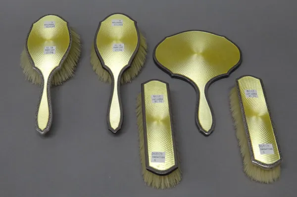 A lady's silver and yellow enamel mounted five piece part dressing set, comprising; a hand mirror, Birmingham 1922, a pair of haribrushes and a pair o