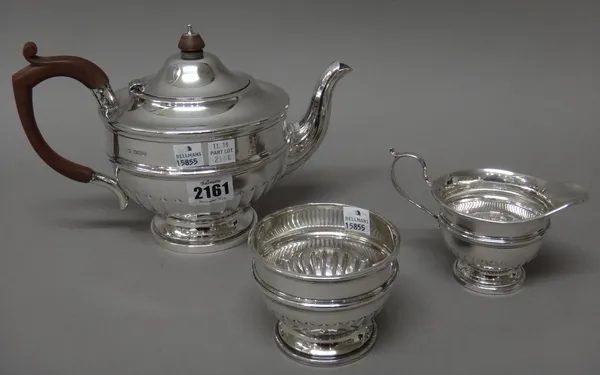 A silver three piece tea set, comprising; a teapot, a sugar bowl and a milk jug, each piece with partly fluted decoration, the teapot with composition