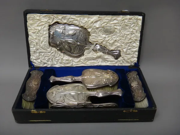 A silver mounted Art Nouveau composite six piece lady's dressing set, each piece decorated with birds, flowers and water lilies within shaped borders,