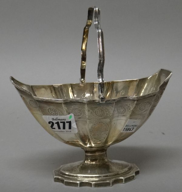 A George III silver sugar basket, of shaped oval panelled form, decorated with an engraved band above a crest within a reeded rim, raised on a shaped