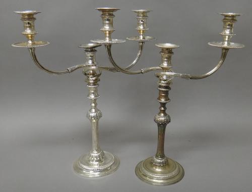 A pair of silver three light table candelabra, each with a fluted column below a foliate decorated knopp to the stem, with scrolling arms and on a cir