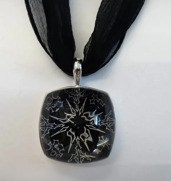 A Baccarat silver mounted glass pendant, the curved square glass pendant having a black and white backing, with a cruciform centre, fitted to a silver