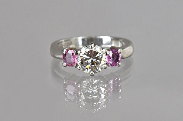 A platinum, diamond and pink sapphire three stone ring, claw set with the circular cut diamond at the centre, between two circular cut pink sapphires,