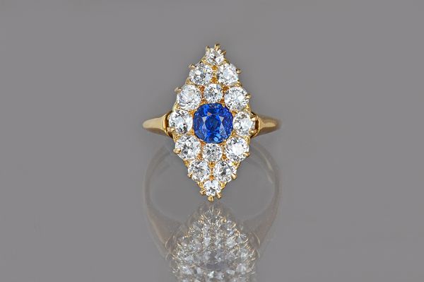 A gold, sapphire and diamond marquise shaped cluster ring, mounted with the cushion shaped sapphire at the centre and otherwise further set with fourt