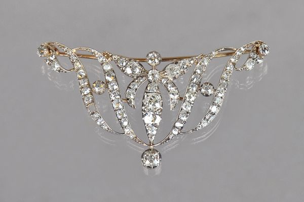 A Victorian diamond brooch, in a shallow scrolling openwork design, mounted with cushion shaped and rose cut diamonds, (one diamond lacking), length 6