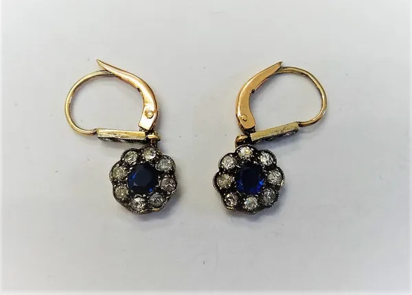 A pair of sapphire and diamond pendant cluster earrings, each mounted with a cushion shaped sapphire at the centre, in a surround of eight cushion sha