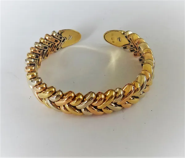 A three colour gold bangle, in a large and small slanting link design, with yellow gold terminals, detailed 750, gross weight 74.7 gms.