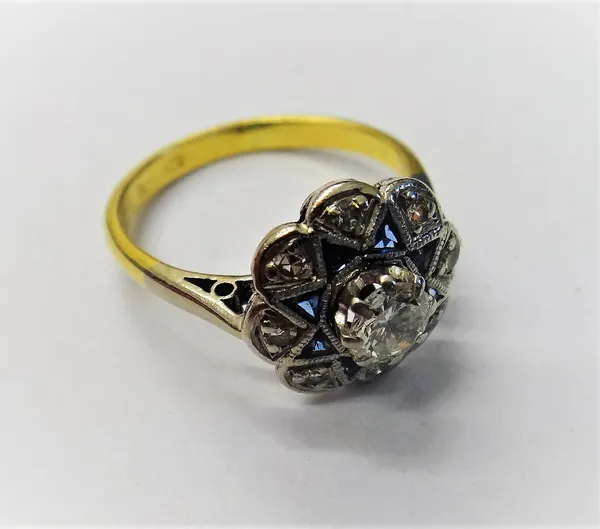 A gold, diamond and synthetic sapphire cluster ring, claw set with the principal circular cut diamond in a surround of eight triangular synthetic sapp