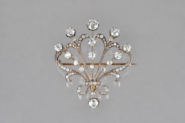 A gold backed and silver set diamond brooch, in an openwork fanned and scrolled design, claw set with cushion shaped diamonds and with the principal d