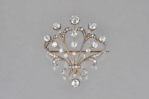 A gold backed and silver set diamond brooch, in an openwork fanned and scrolled design, claw set with cushion shaped diamonds and with the principal d