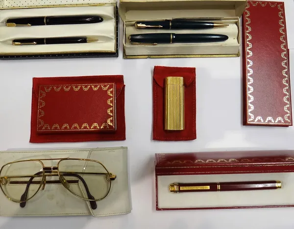 A Cartier Paris gilt metal gas lighter, with fluted decoration, with a booklet and two red pouches, a Cartier Paris gilt and red ballpoint pen, with a