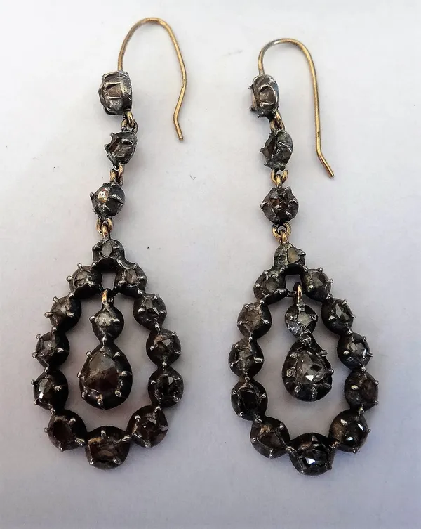 A pair of rose diamond set pendant earrings, each of drop shaped openwork form, with a swing centre and with a three stone diamond surmount, silver fr