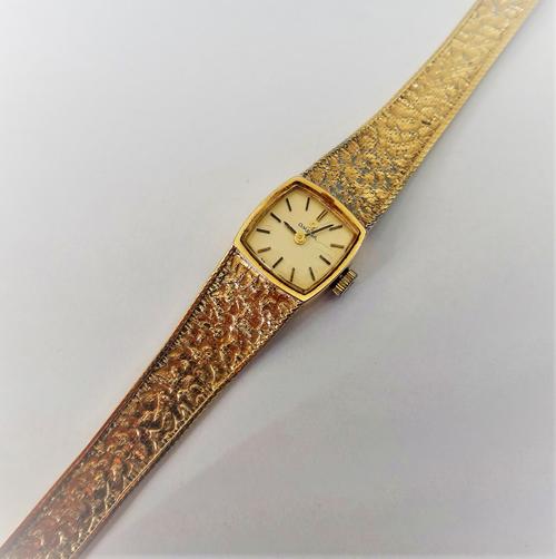 An Omega 9ct gold lady's bracelet wristwatch, the signed curved square dial with black baton numerals, on a tapering textured link bracelet, the 9ct g