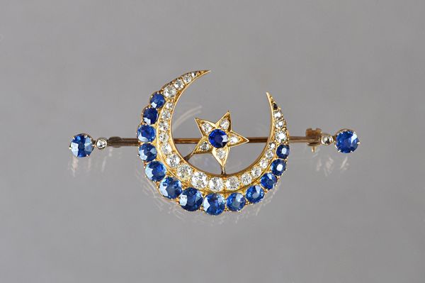 A gold, sapphire and diamond brooch, designed as a crescent enclosing a five pointed star, mounted with cushion shaped sapphires and with cushion shap