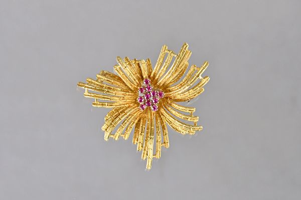 An 18ct gold and ruby brooch, in a stylized starburst design, with a textured finish, claw set with a cluster of ciruclar cut rubies to the centre, im