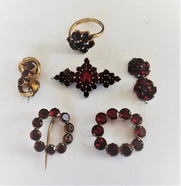 A foil backed flat cut garnet set brooch, in an openwork design, a similar garnet set brooch, (the pin lacking), two further garnet set brooches, a 9c