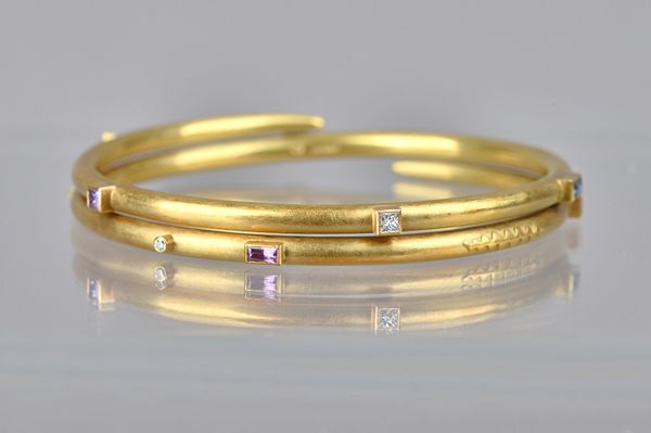 An 18ct gold, diamond, pink and blue sapphire bangle, by Mark Nuell, of spiral circular form, decorated with ridged motifs, otherwise with a matt fini