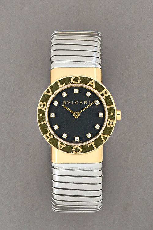 A Bvlgari diamond set, gold and steel lady's bangle wristwatch, the signed black dial with diamond set numerals and with plain gilt hands, further det