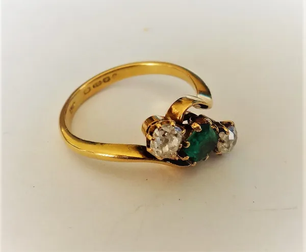 An 18ct gold, emerald and diamond three stone ring, claw set with the cut cornered rectangular step cut emerald at the centre, between two cushion sha