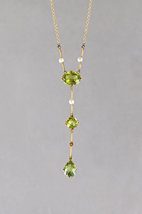 A gold, peridot and seed pearl pendant necklace, mounted with a pear shaped peridot to the drop, a circular cut peridot to the centre and with an oval